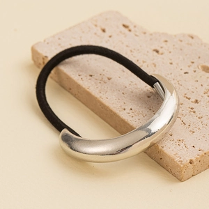 Close-up of minimalist black elastic hair tie with polished silver metallic cross detail
