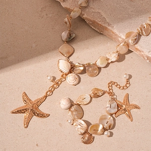 Golden ocean jewelry set with starfish pendants, shell accents and pearls on stone