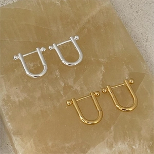Detailed close-up of U-shaped horseshoe earrings in gold and silver on amber stone