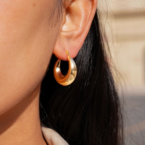 Close-up of chunky 18k gold plated hoop earrings with a polished mirror finish on model