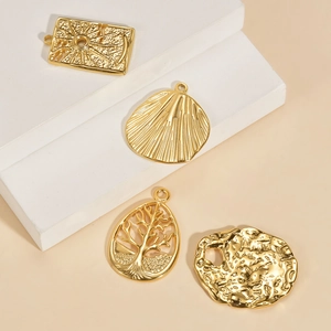 Detail of four golden stainless steel charms featuring Tree of Life and celestial designs