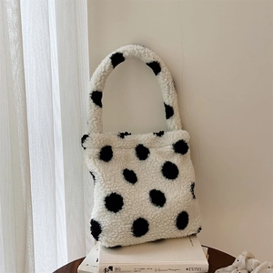 Mini sac à main en polaire à pois sur un présentoir de livre blanc minimaliste