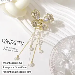 Detailed view of butterfly hair claw with white rhinestones and pearl tassels on white fabric
