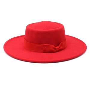 Close-up of the red wool boater hat featuring a flat top and matching grosgrain ribbon bow