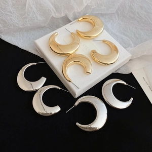 Polished C-shape stud earrings in gold and silver finish on a display box