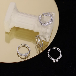 Silver layered star and pearl open rings set with zircon accents on a mirror display