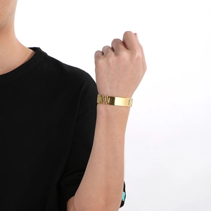 Close-up of golden stainless steel watch band style bracelet with a polished rectangular plate