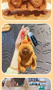 Detailed plush capybara keychain with orange hat and golden ring on a canvas bag