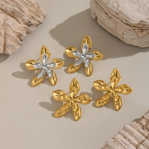Two-tone 18K gold and silver floral stud earrings on natural rock and wood background