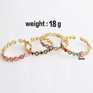 Detailed view of three gold-plated open bangles featuring colorful evil eye and heart charms