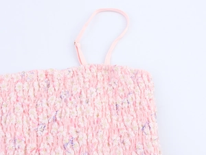 Détail du tissu froncé rose avec textures florales en 3D et fines bretelles de robe