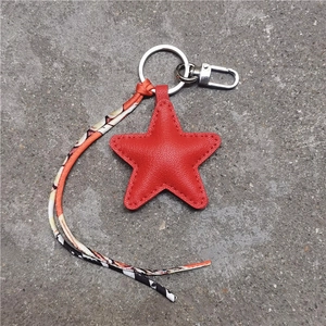 Macro detail of red star leather keychain with printed ribbon on concrete background
