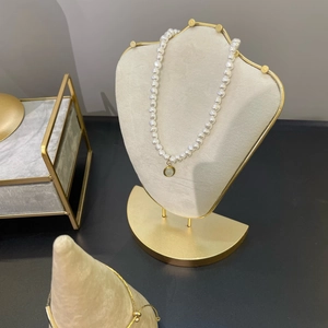Elegant white pearl necklace with golden trim pendant on professional jewelry display stand