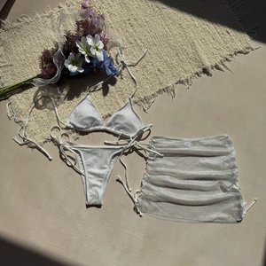 Détail d'un bikini 3 pièces en tricot blanc avec jupe de plage en maille transparente