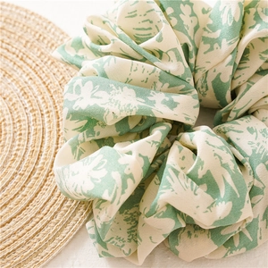 Detailed texture of fabric floral scrunchie with green plant patterns on straw mat