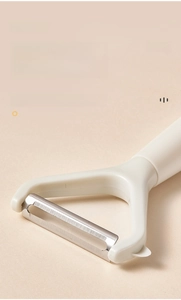 Close-up of rotatable stainless steel blade on a cream multifunctional vegetable peeler
