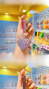 Detail showing hand-held rhinestone heart keychain with sparkling pink gems and leather strap
