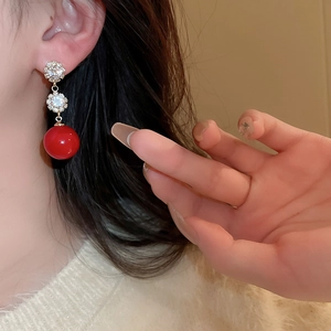 Close-up of elegant red spherical pearl drop earrings with zircon and gold plating