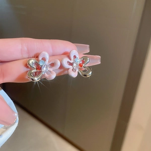 Détail de boucles d'oreilles fleur en émail rose avec bord argenté et gemmes colorées