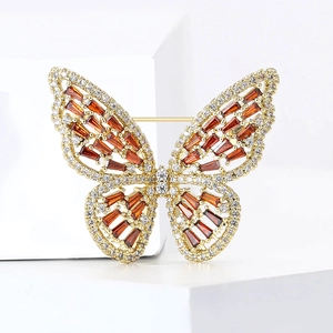 Detailed macro view of a luxury butterfly brooch with orange crystals and micro-pave zircons