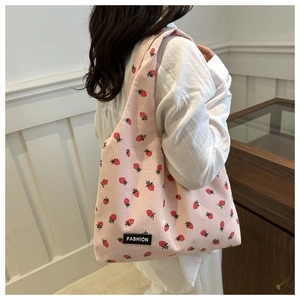 Detailed texture of pink corduroy tote bag with red strawberry pattern on shoulder