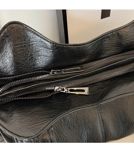 Detail of premium black leather tote with dual silver zippers and smooth metallic pulls