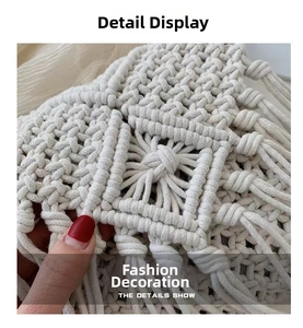Close-up of the hand-woven macramé texture and tassel detail on a beige straw beach bag