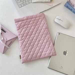 Close-up of pink quilted diamond pattern tablet sleeve with brand tag on desk