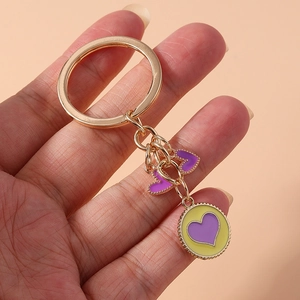 Close-up of gold metal keychain with purple heart charms and round pendant accessory