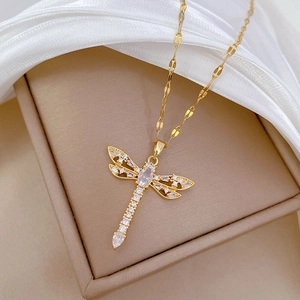 Macro detail of a gold dragonfly pendant necklace with sparkling cubic zirconia on silk