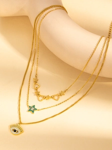 Dettaglio collana multistrato in titanio dorato con ciondoli a stella, cuore e occhio