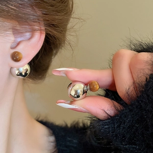 Detail of silver geometric stud earrings featuring brown tiger eye and high-shine metallic spheres