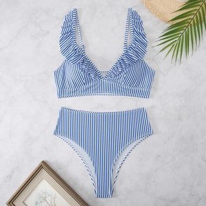 Detailed flat lay of blue striped high-waisted bikini with ruffled V-neck on marble