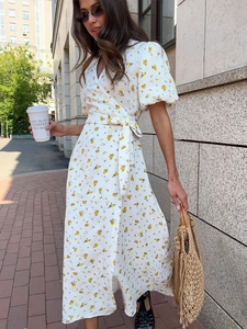 Detail of white wrap dress with yellow floral print, V-neckline and waist tie closure