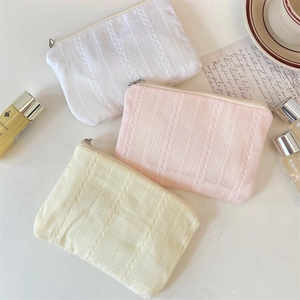 Detail shot of lace textured makeup bags in white and pink on a warm aesthetic background