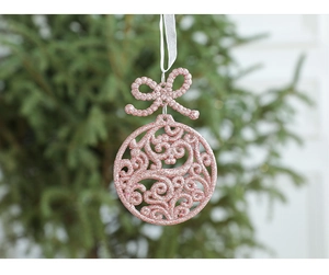 Pink Christmas bauble with glitter and bow hanging on a white ribbon in a festive setting