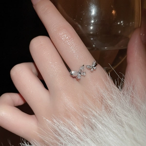 Detailed view of adjustable double butterfly ring with sparkling zircon inlays on fingers
