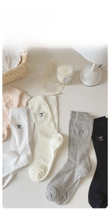 Close-up of ribbed knit crew socks featuring elegant black embroidered bow details