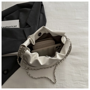 White pleated cloud bag detail showing interior capacity with chain strap on a blazer