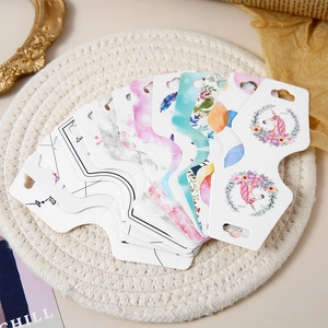 Assorted jewelry display cards with floral and unicorn patterns on a woven mat