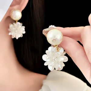 Elegant floral pearl earrings with white flower petals on model for high-end fashion look