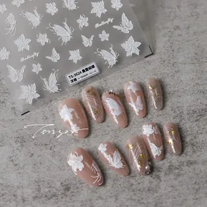 Detail of 3D embossed butterfly and white flower nail decals on elegant marble surface