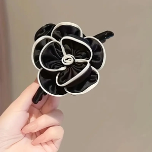 Detailed close-up of a black satin flower hair claw clip with elegant white edges