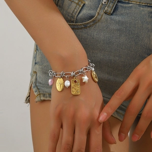 Close-up of stylish stainless steel charm bracelet featuring pink heart and gold coins
