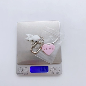Pink heart LOVE pendant and plush cat keychain weighing 18.4g on a digital scale
