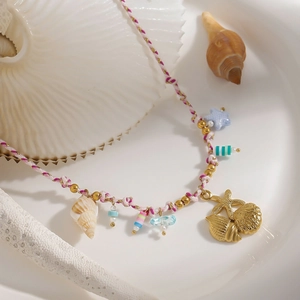 Detail einer gewebten Strandkette mit Muschel- und Seesternanhängern auf einem Tablett