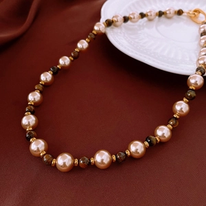 Détail d'un collier en perles et œil de tigre sur velours avec fermoir en T doré