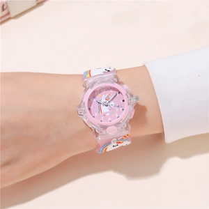 Close-up of pink unicorn kids watch with silicone strap and glowing LED dial on wrist