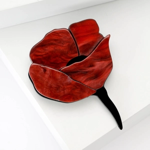 Elegant red acrylic rose flower brooch with black petal edges on white geometric background