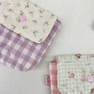 Macro shot of quilted mini storage bags with plaid patterns and snap button details